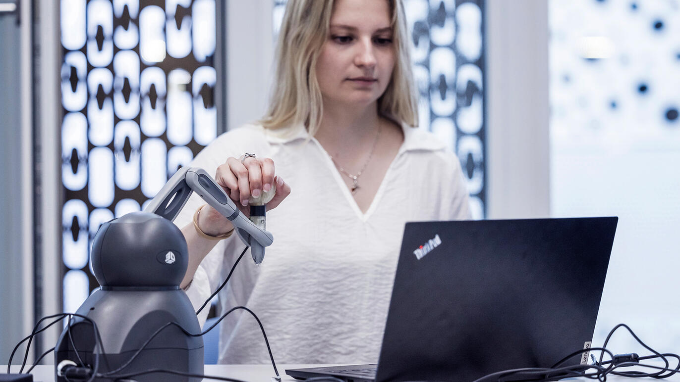 frau bedient Roboter vor Notebook