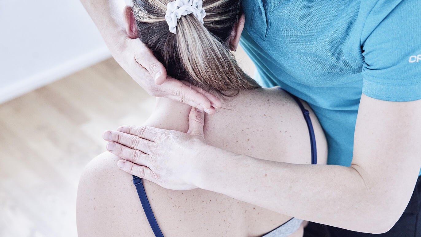 Physiotherapeutin arbeitet am Nacken einer Patientin