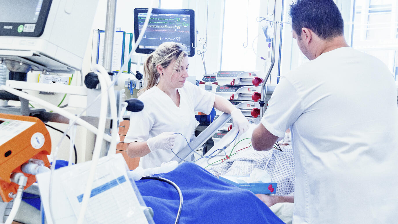 Zwei Pflegefachpersonen kümmern sich um einen Patienten auf der intensivstation.