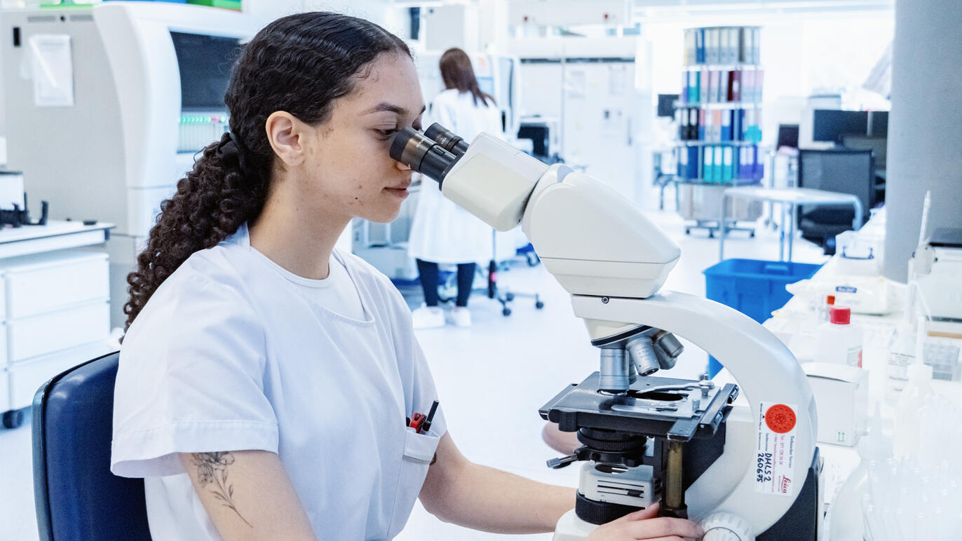 Mikrobiologin durchsucht eine Probe unter dem Mikroskop