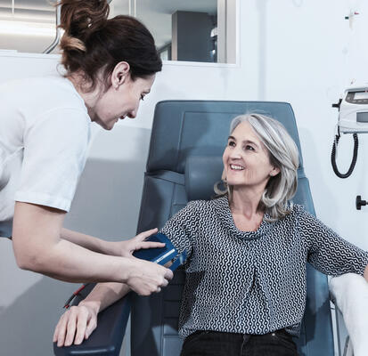 Pflegefachperson misst Blutdruck einer Patientin