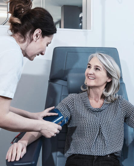Pflegefachperson misst Blutdruck einer Patientin
