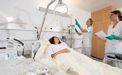 Zwei Pflegefachfrauen kümmern sich um die Patientin und hängen Infusion an