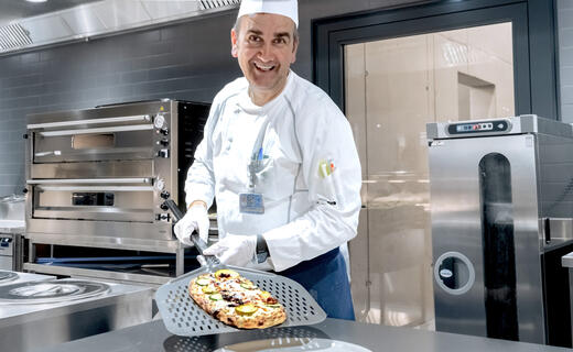 Koch präsentiert frisch gebackene Pizza