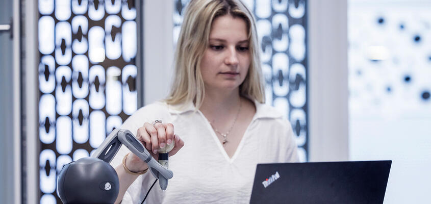 frau bedient Roboter vor Notebook