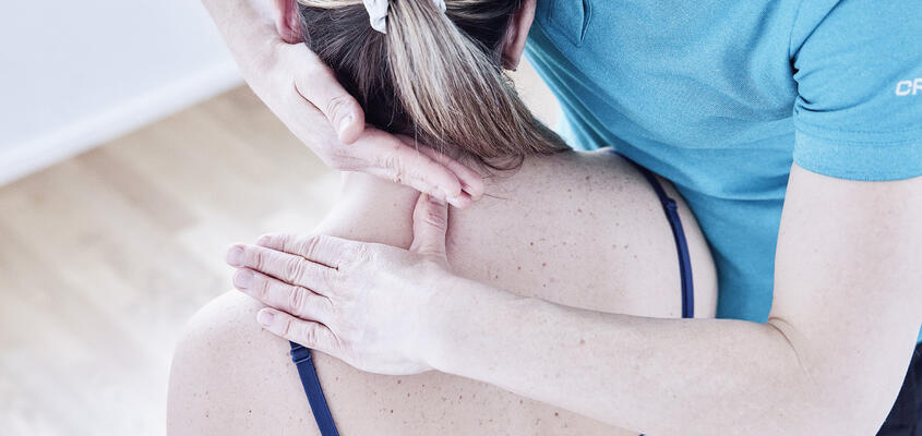 Physiotherapeutin arbeitet am Nacken einer Patientin