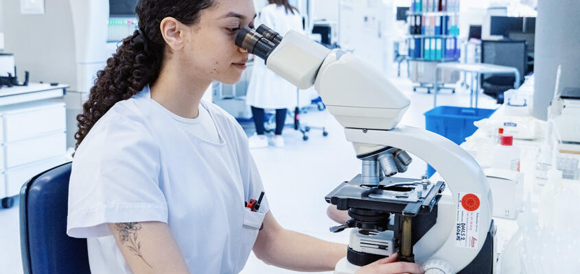 Mikrobiologin durchsucht eine Probe unter dem Mikroskop